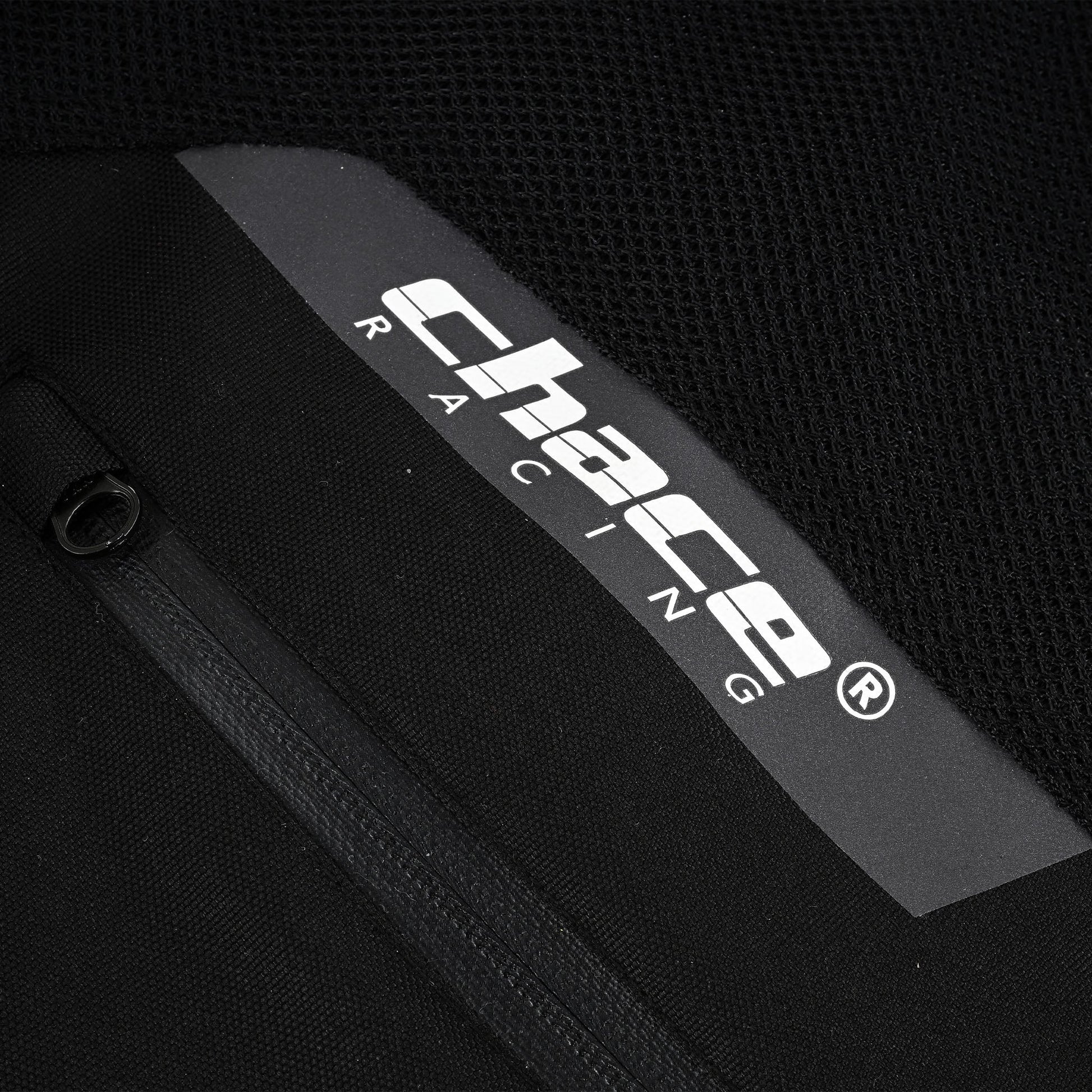 Close-up of the jacket's side, showing the white reflective "Chace Racing" logo strip positioned above a partially opened black zipper pocket or vent near the mesh panel.