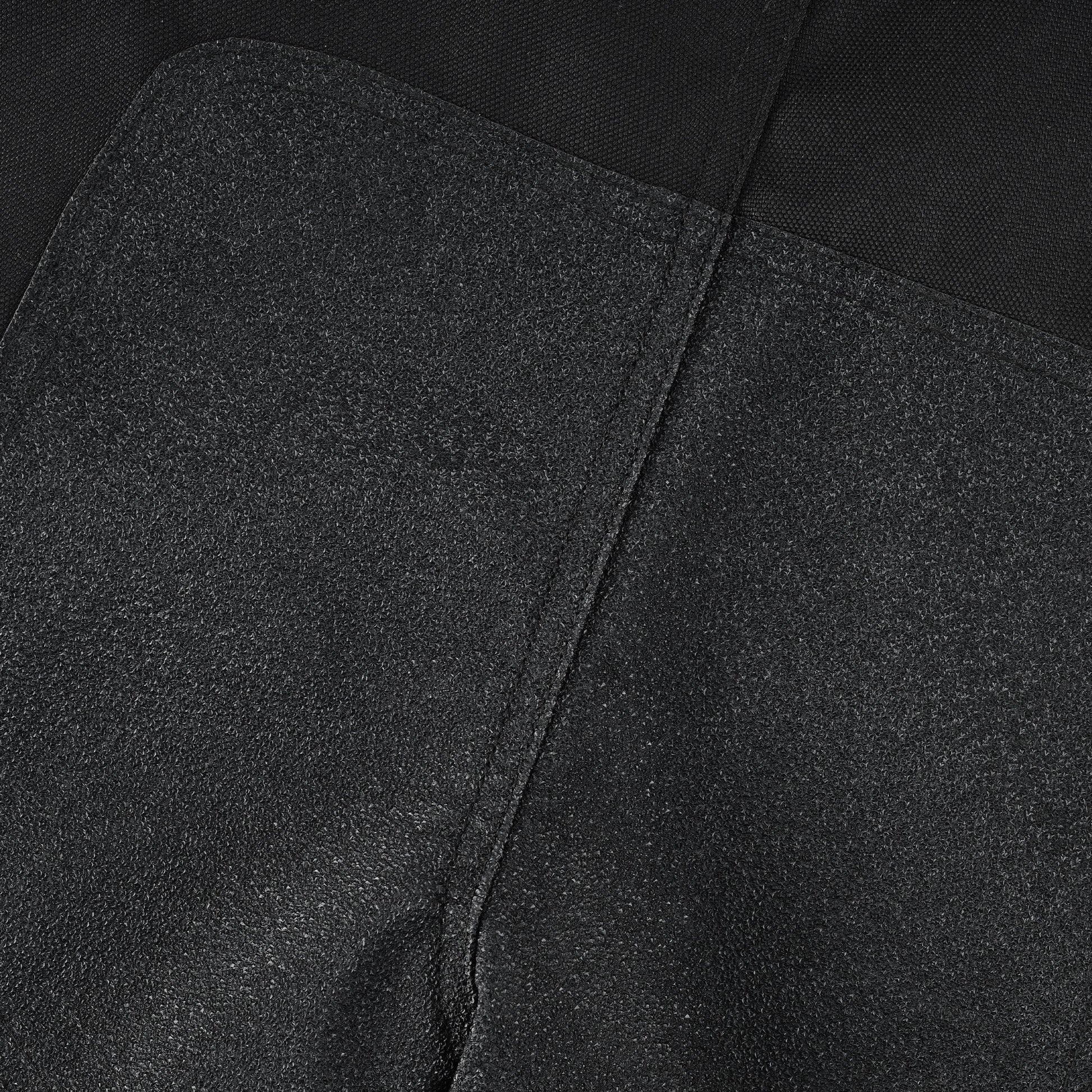 Extreme close-up of a dark, textured, abrasion-resistant panel (likely non-slip or reinforced textile) integrated into the trousers, showing the rough, durable surface.