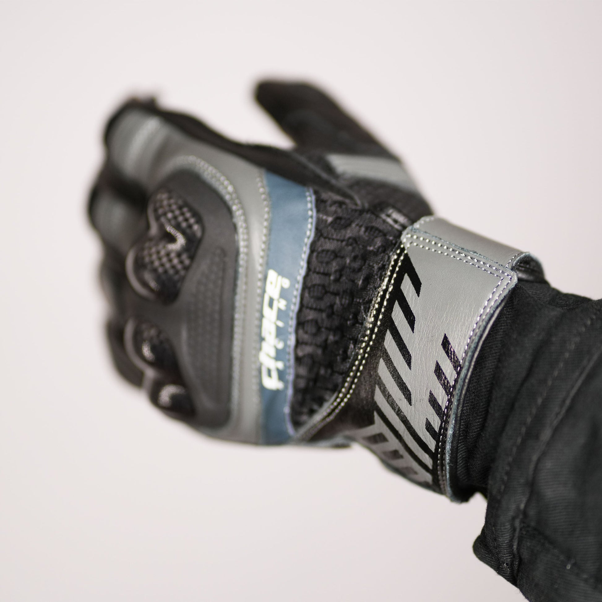 Close-up of the glove's wrist and gauntlet area, highlighting the adjustable closure strap, the Chace Racing logo, and the contrast between the grey leather and black mesh/textile.