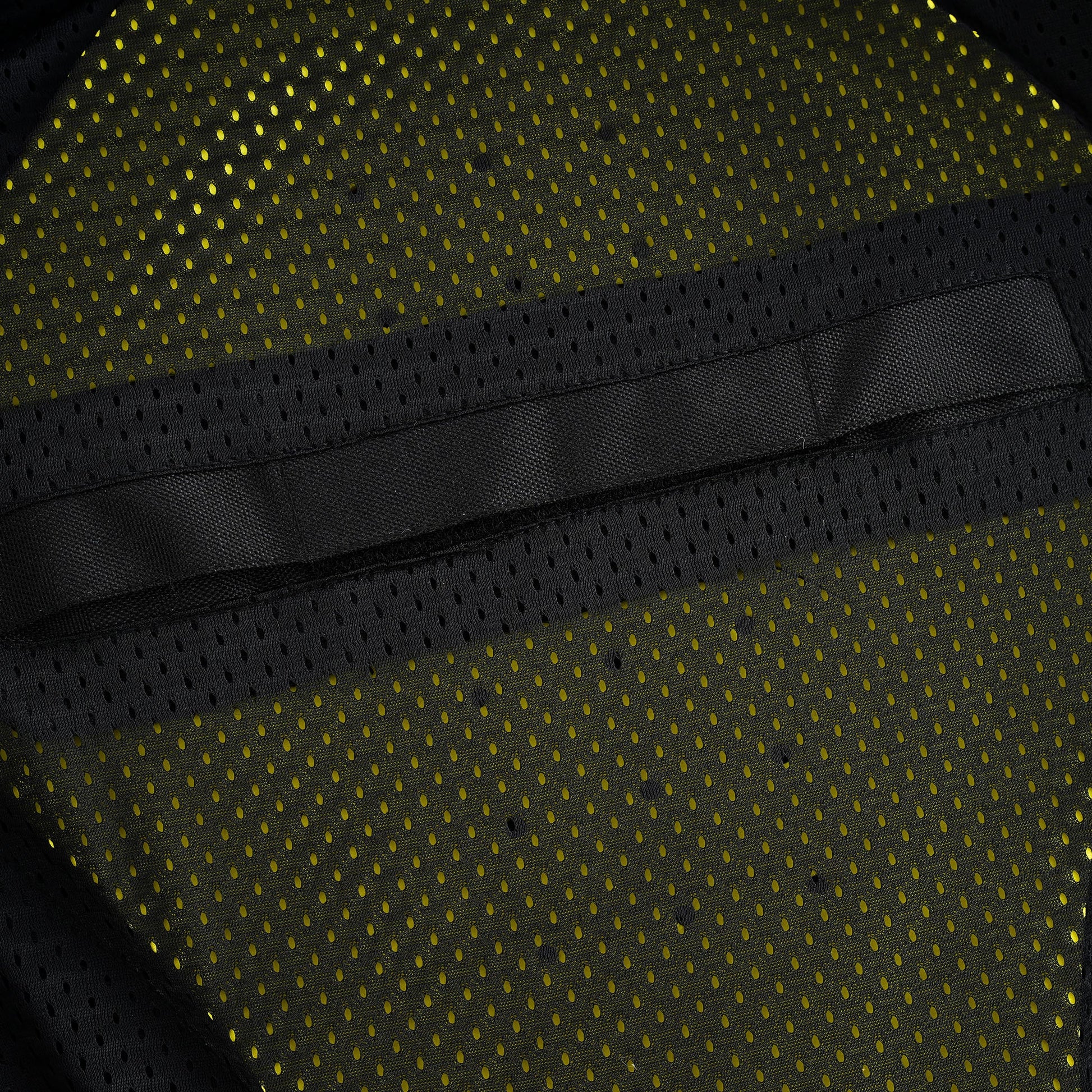 Close-up view of the jacket's breathable mesh lining, with a horizontal black textile strip sewn into the mesh, indicating the sleeve for the back protector pad.