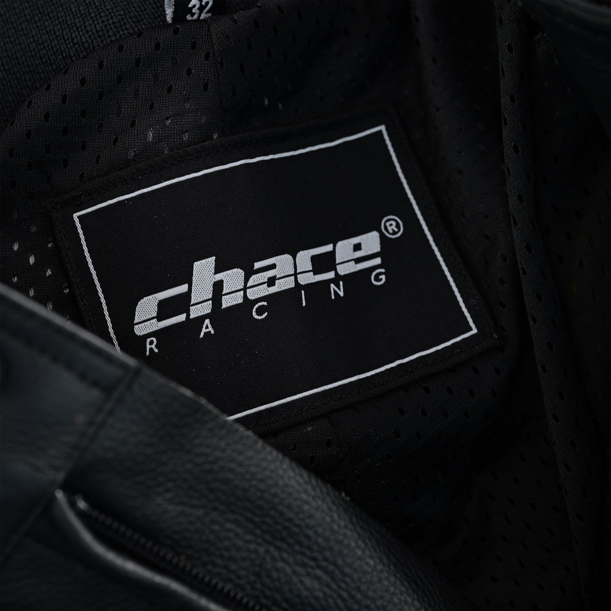 Close-up of the trousers' interior, showing the black breathable mesh lining and the woven white and black "Chace Racing" brand tag.