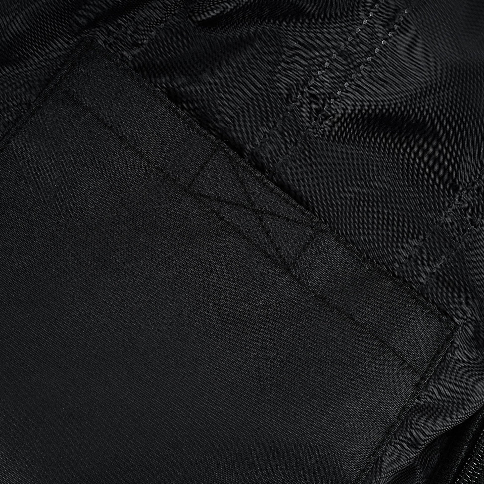 Close-up of a large, black internal patch pocket sewn onto the thermal or windproof lining, showing the reinforced stitching at the top corners.