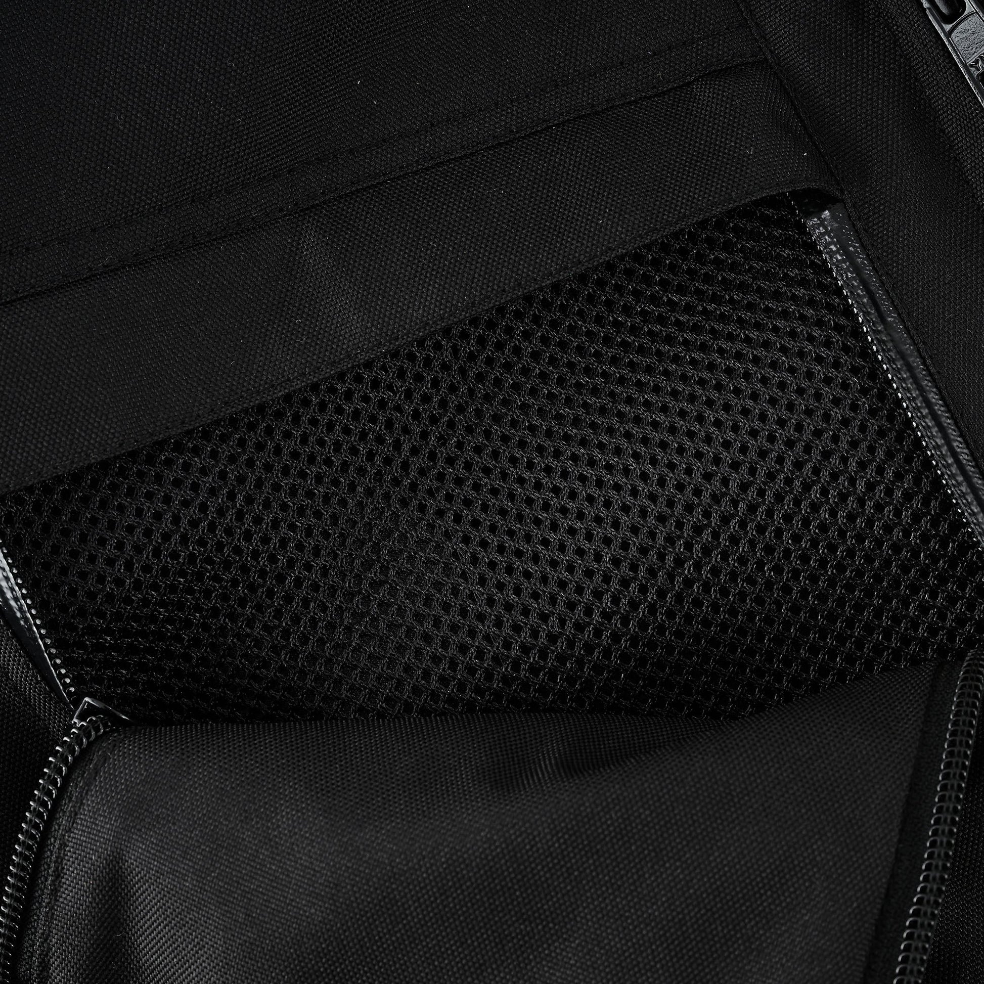Close-up of an open internal security pocket with a zipper, revealing a black breathable mesh lining inside the pocket for storage or ventilation.