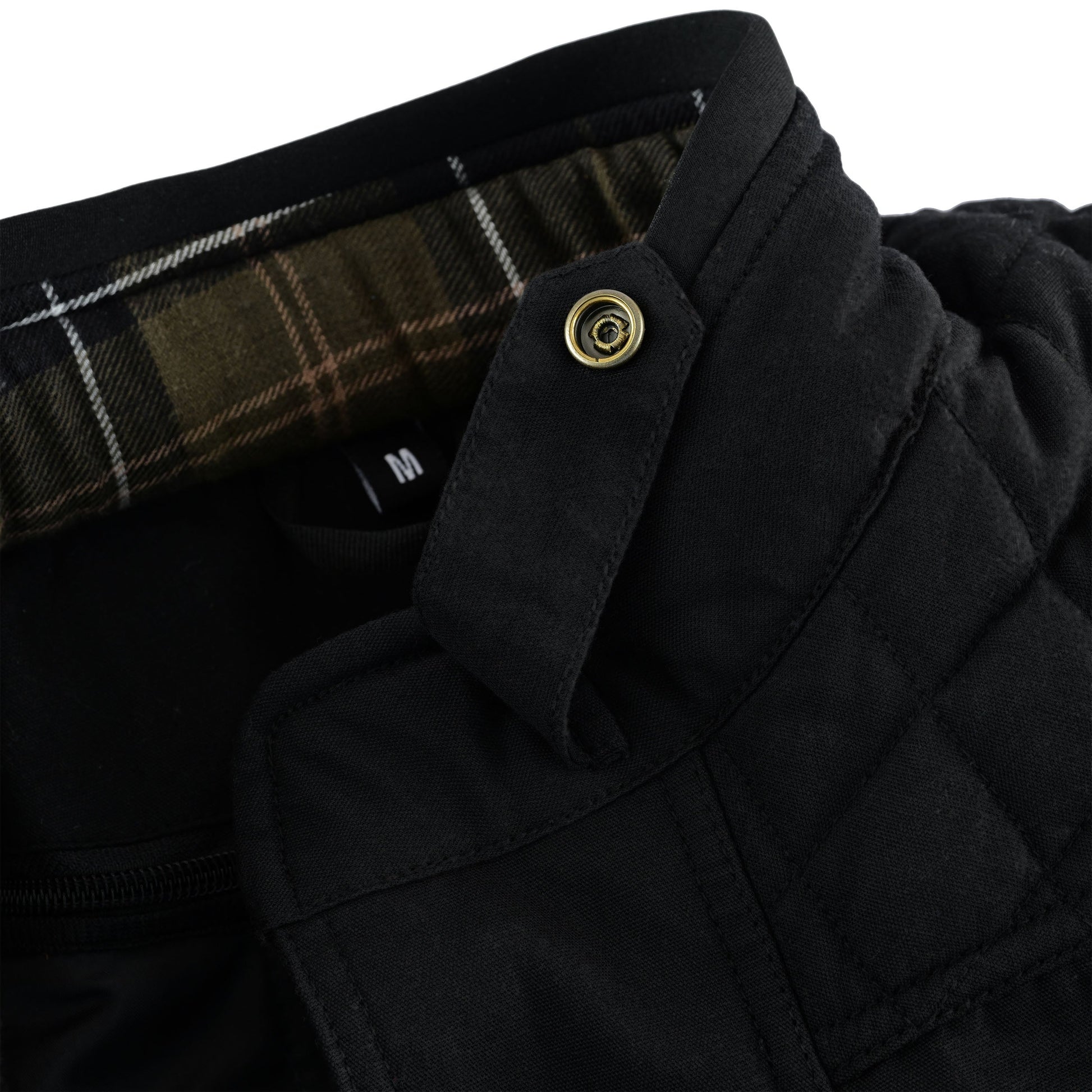 Close-up of the jacket's stand collar, showing the tartan plaid lining on the interior, a black collar strap with a gold snap button closure, and the 'M' size tag.