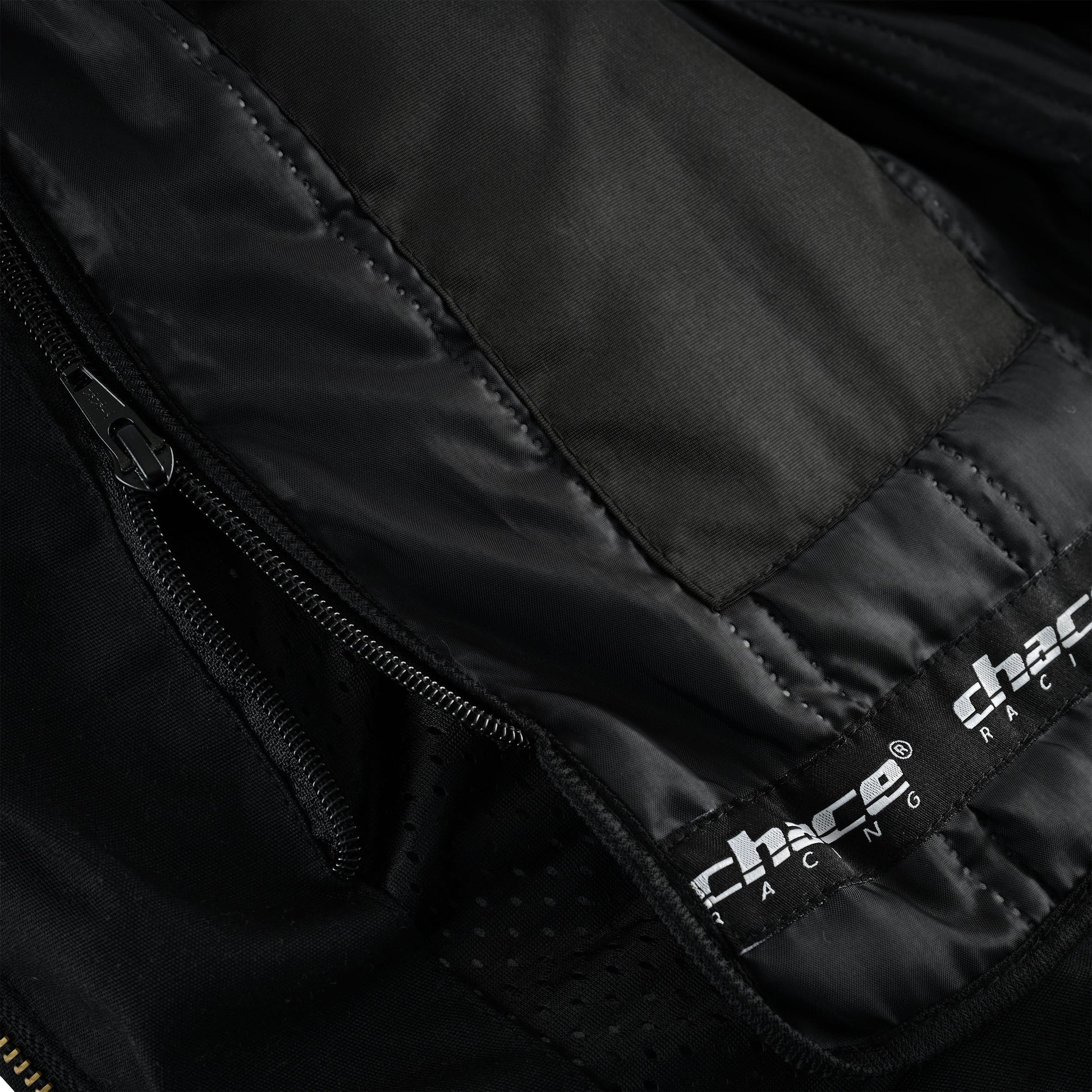 Close-up of the interior jacket lining, showing the heavy-duty zipper used to attach the quilted thermal liner and the visible "chace racing" logo on the base of the mesh liner.